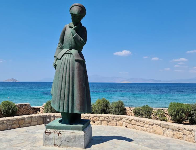 Am Straßenrand vor dem Museum steht eine große Bronzeskulptur einer Frau in traditioneller Tracht, die den Titel „Griechische Mutter“ trägt.